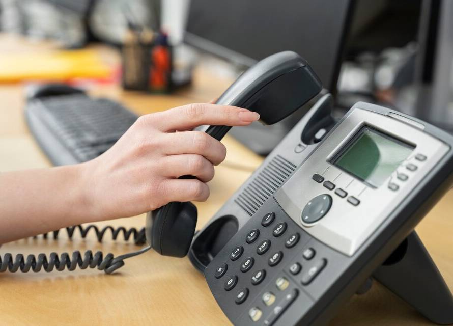 A VoIP phone with a digital display showing a VoIP phone number